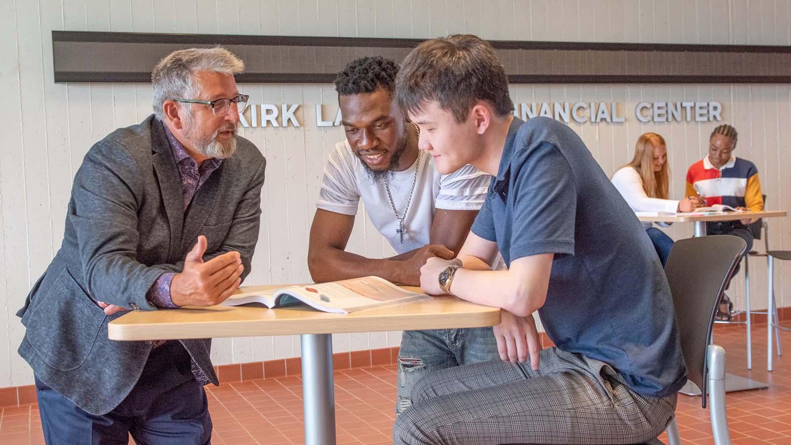 Two business students having a discussion with a professor