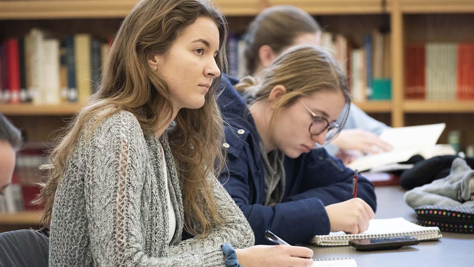 Female students listening to lecture in Catholic studies classroom