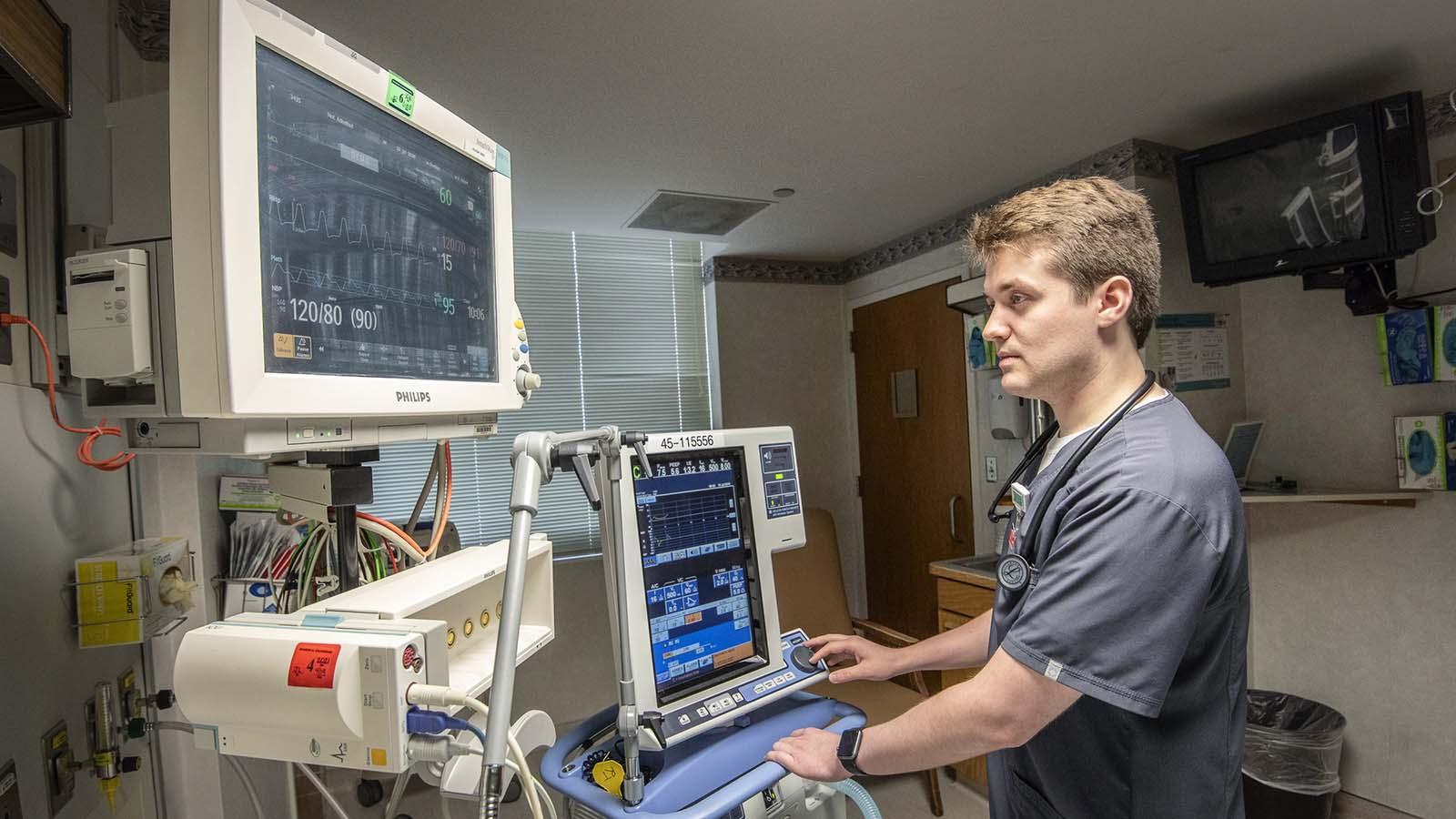 Male respiratory therapy student monitoring vitals of patient