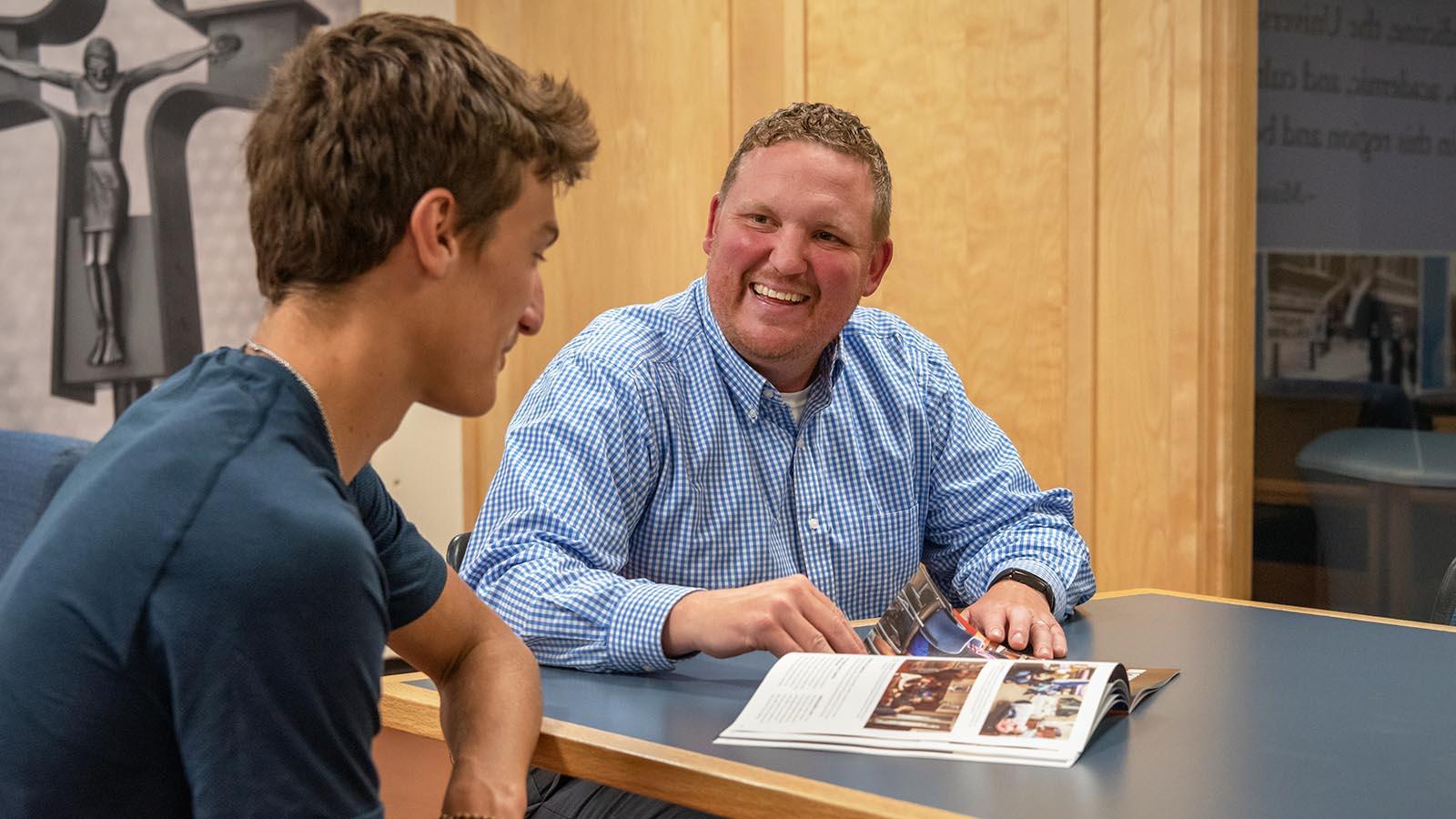 Director of Admissions talking with student while looking at university viewbook