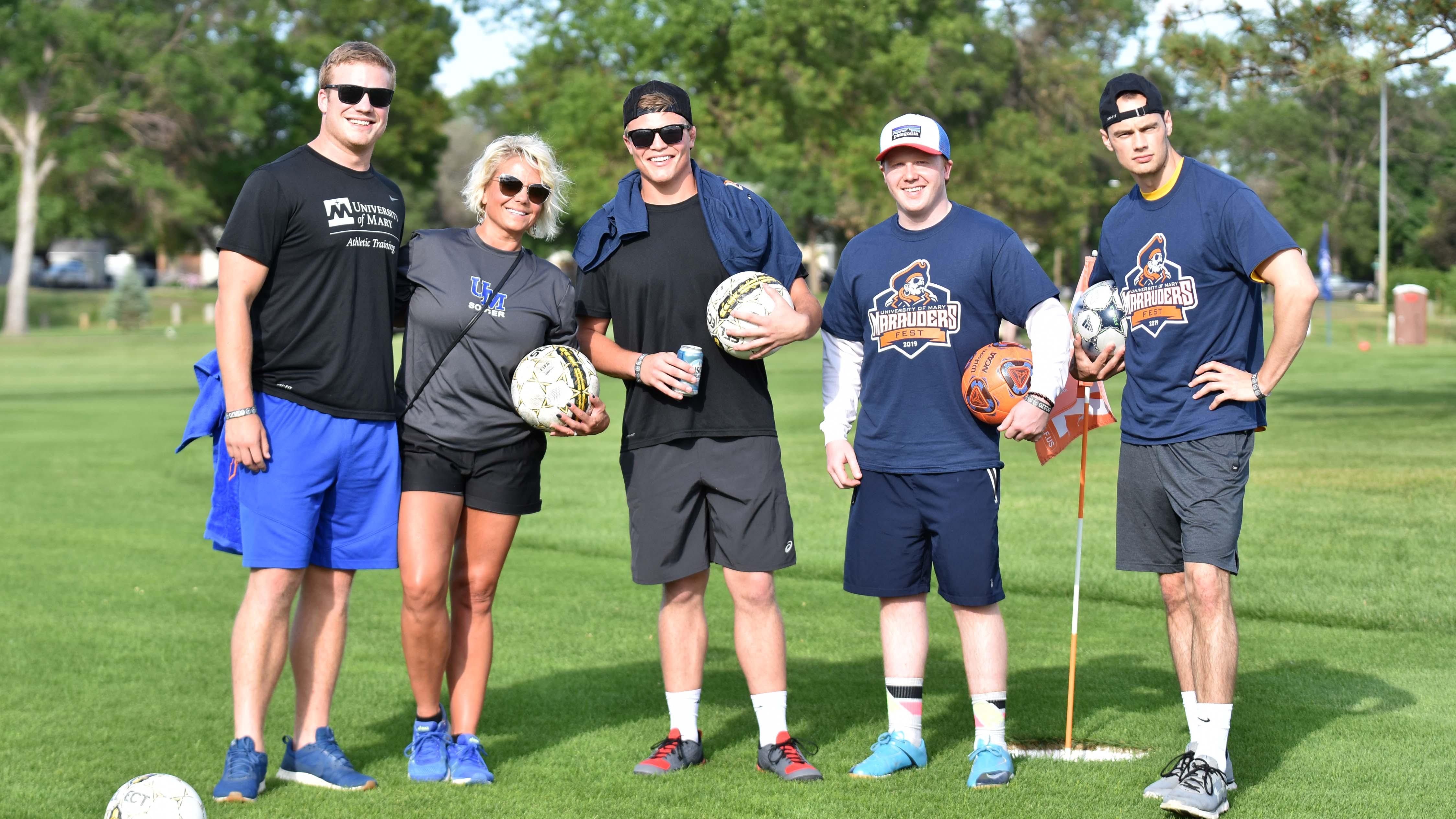 Five Marauders Fest participants holding soccer balls and smiling 