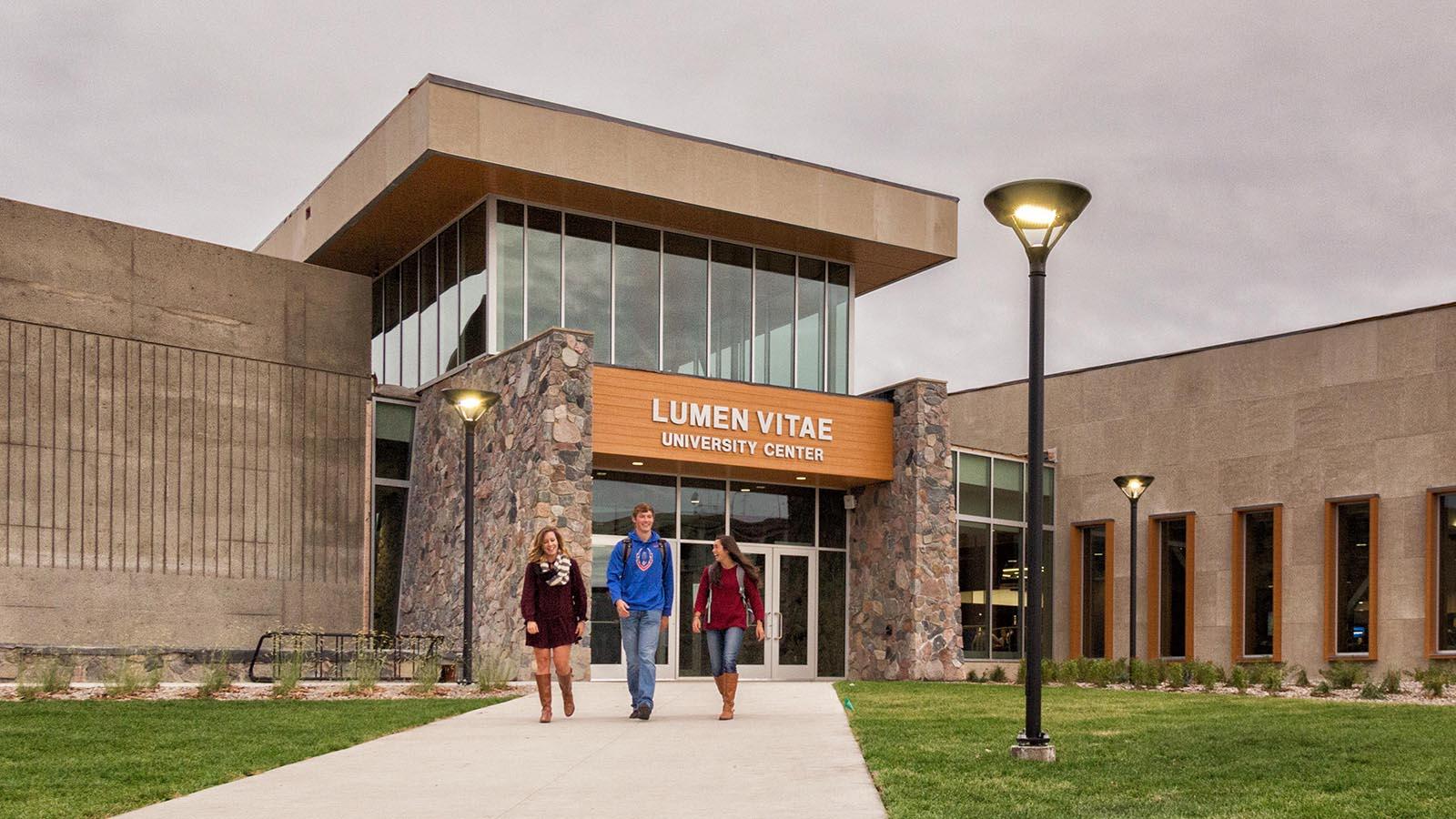 Three students walking outside of the Lumen Vitae University Center.