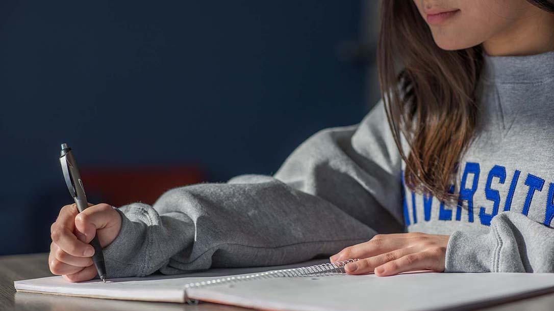 Closeup of female student writing in notebook