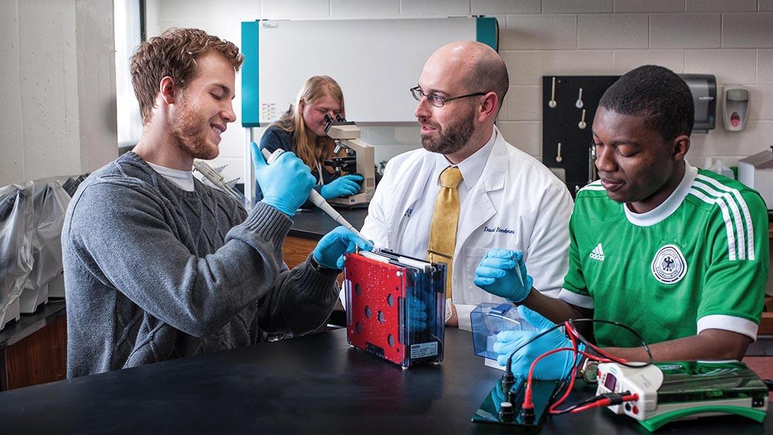 Chemistry teacher helping students place chemicals into beakers.