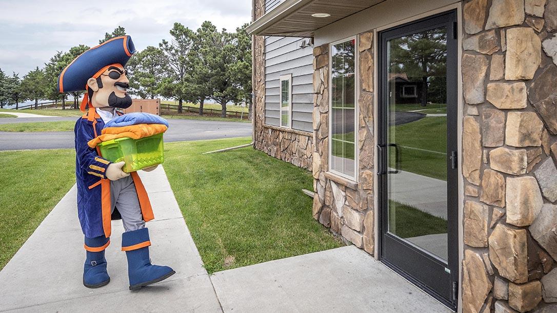 Max the Marauder carrying a box of towels into one of the on-campus apartments.