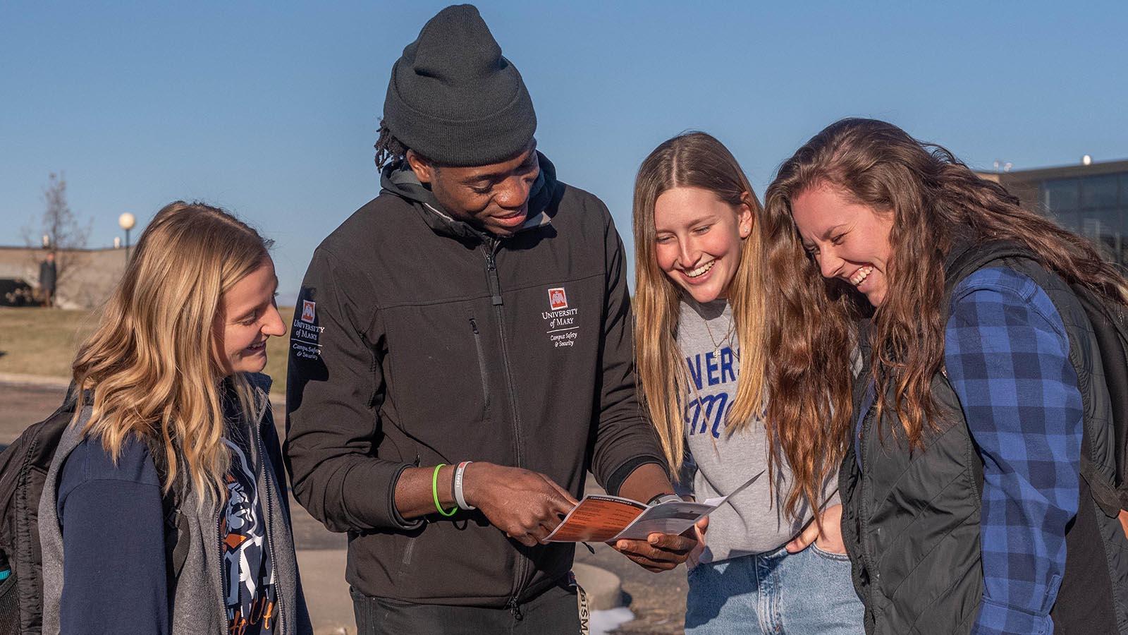 Campus Safety & Security employee showing three female students a campus map.