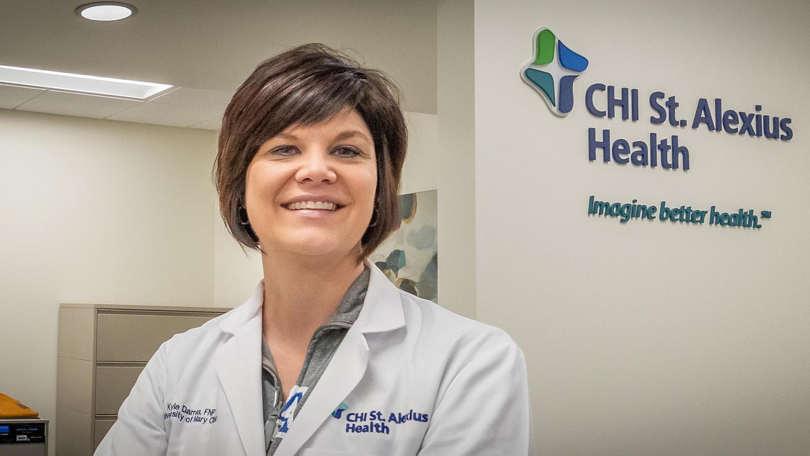 Kyle Darras, University of Mary physician, standing in front of the CHI St. Alexius Health sign.