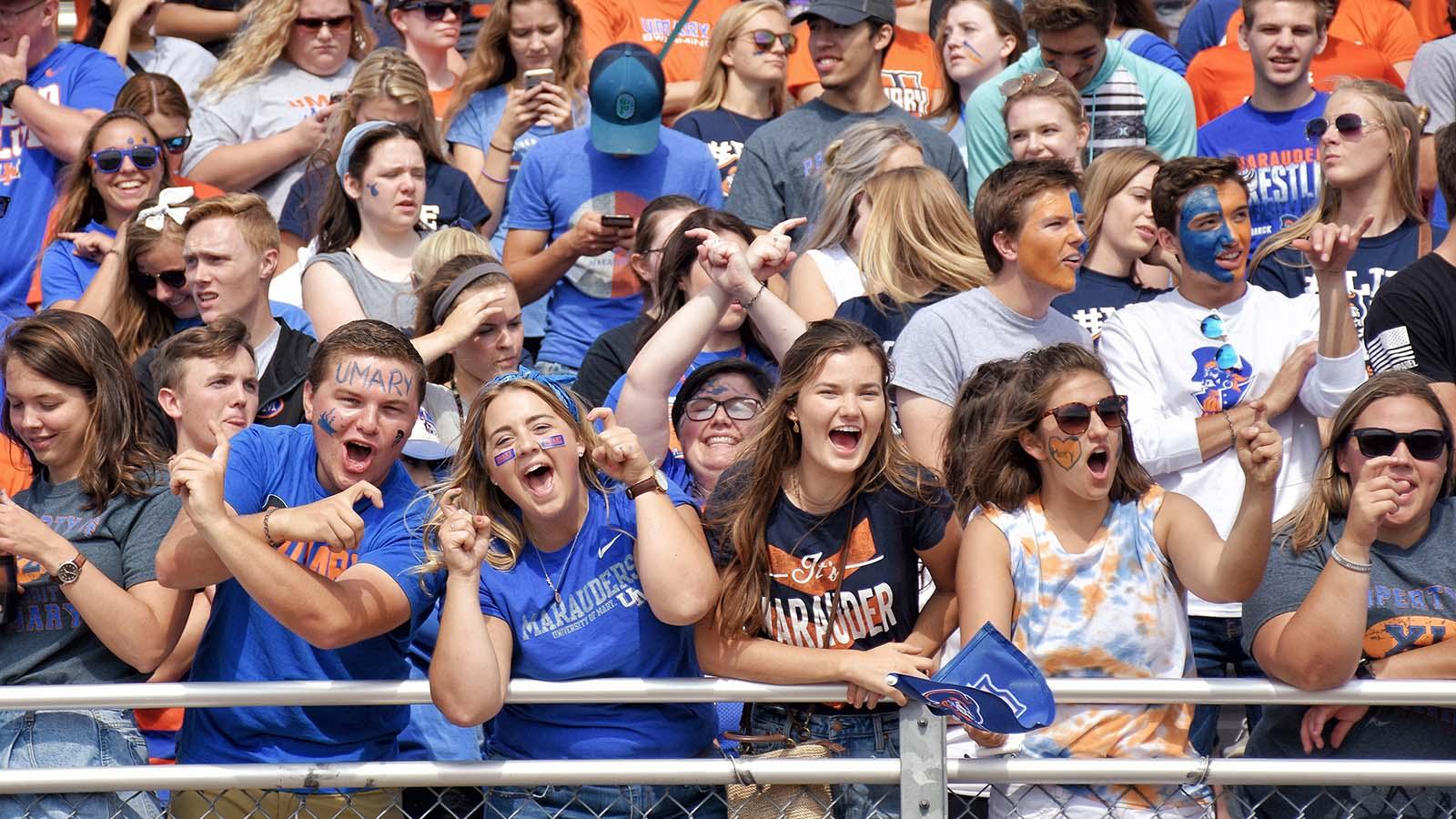 Hundreds of loud and energetic fans cheering in the student section at a home Marauders football game.