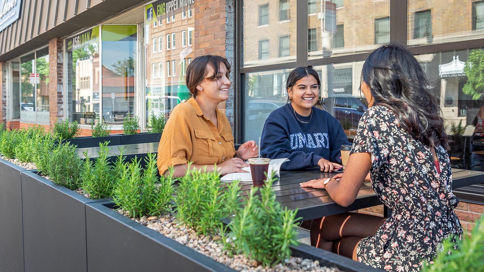 Three happy college students having coffee at a coffee shop in a growing and vibrant downtown Bismarck.