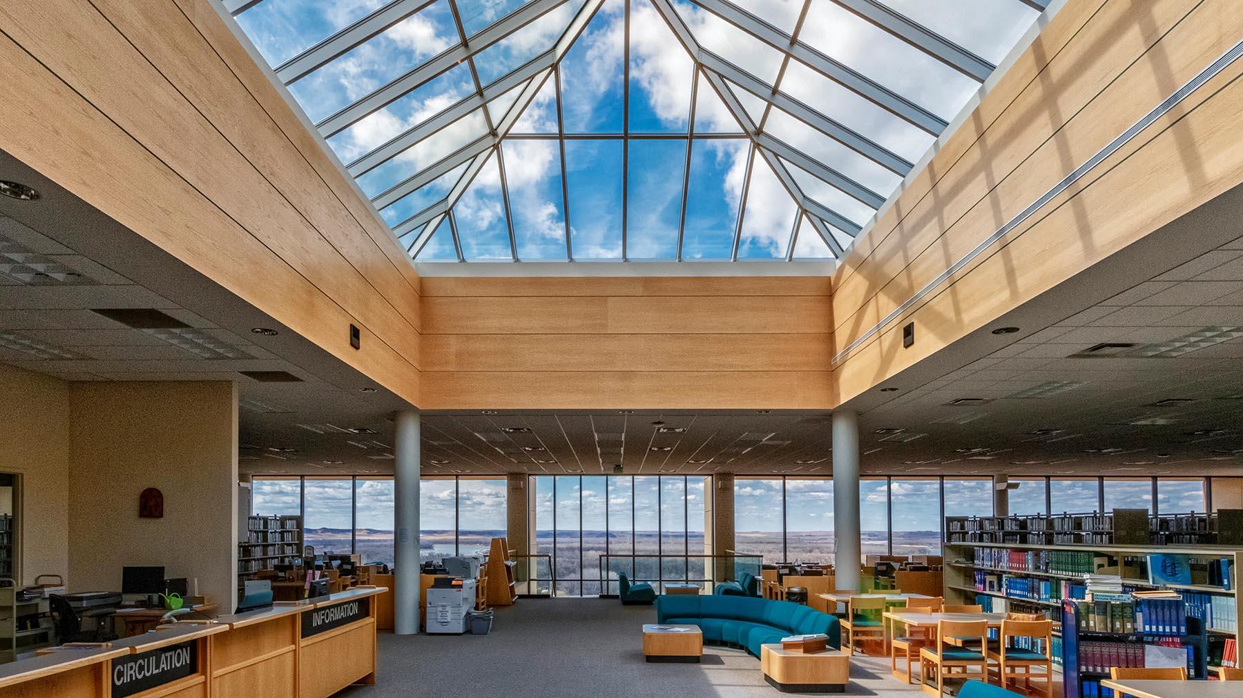 View of the library from the entrance, showcasing large skylight and west wall of windows looking out to Missouri River Valley