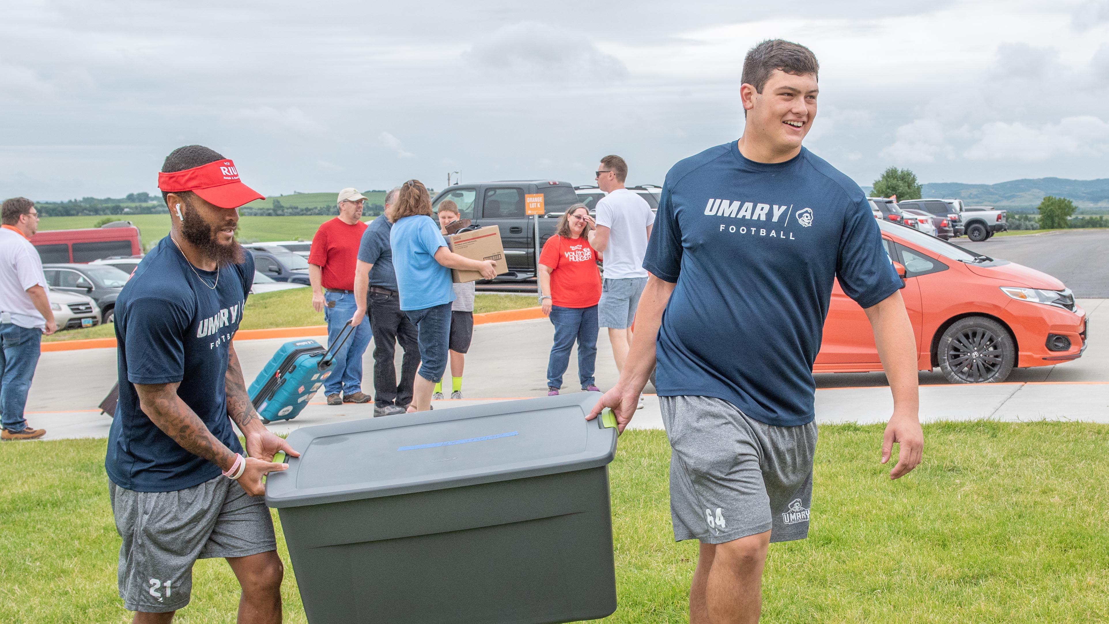 Two University of Mary football players helping during move in week.