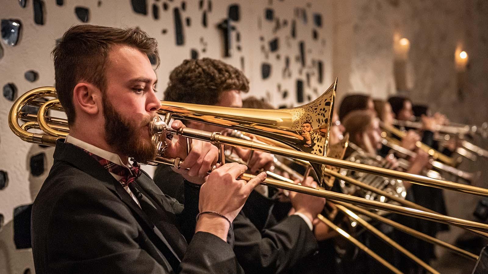 Trombone players performing as part of brass ensemble.