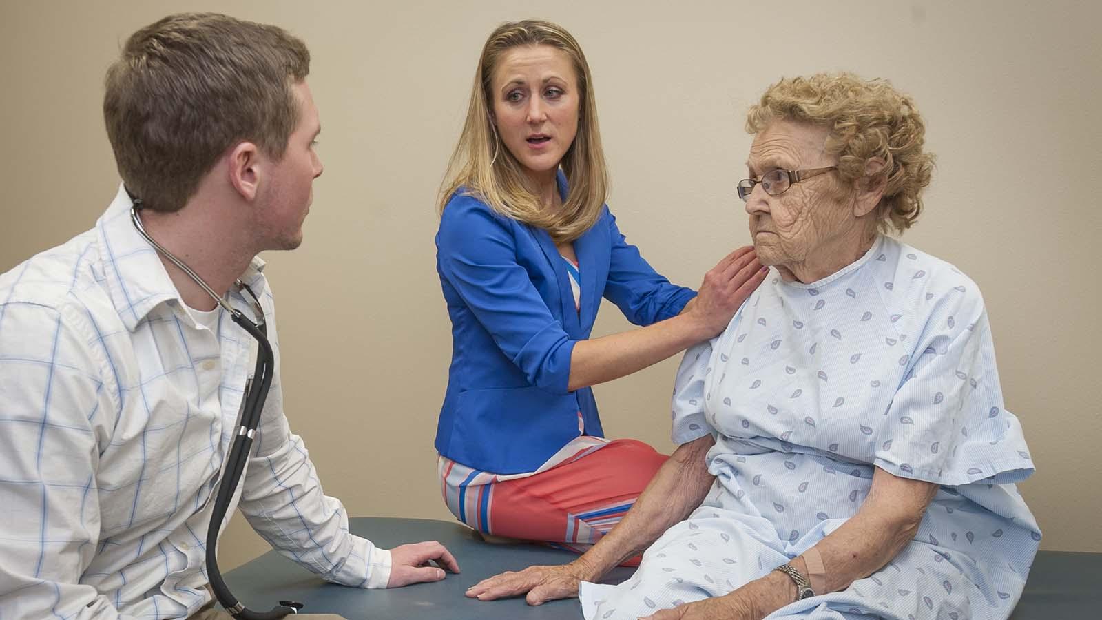 Physical therapy doctoral student and instructor meet with elderly client at the physical therapy clinic