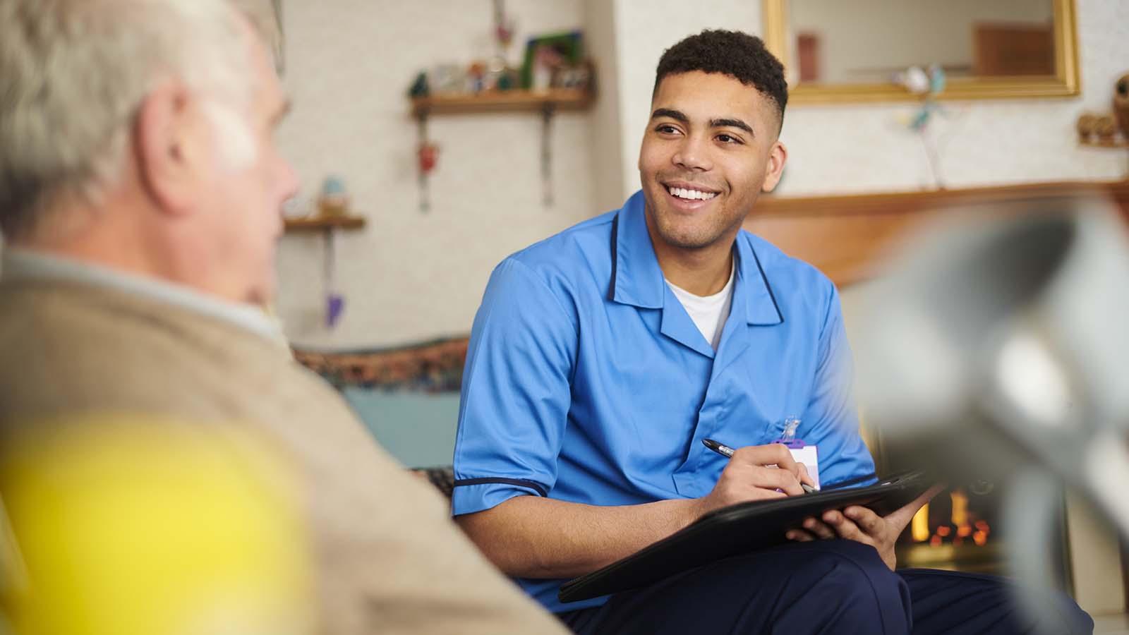 Young male social worker meeting with an elderly man in his home
