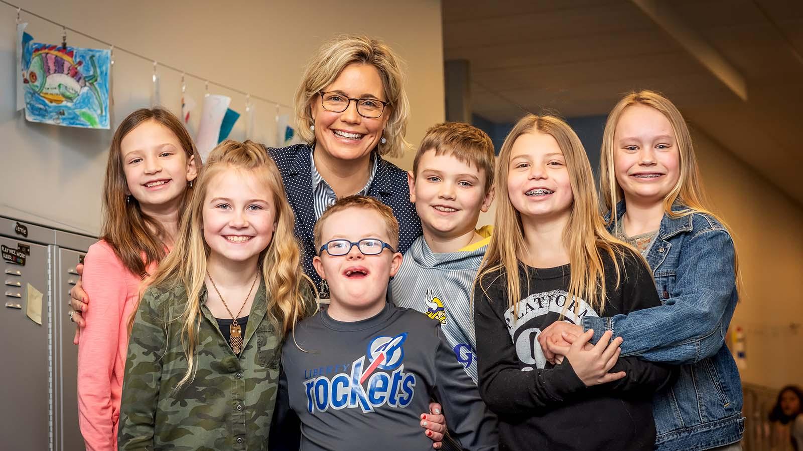 Group of smiling elementary students and teacher in the hallway of a school