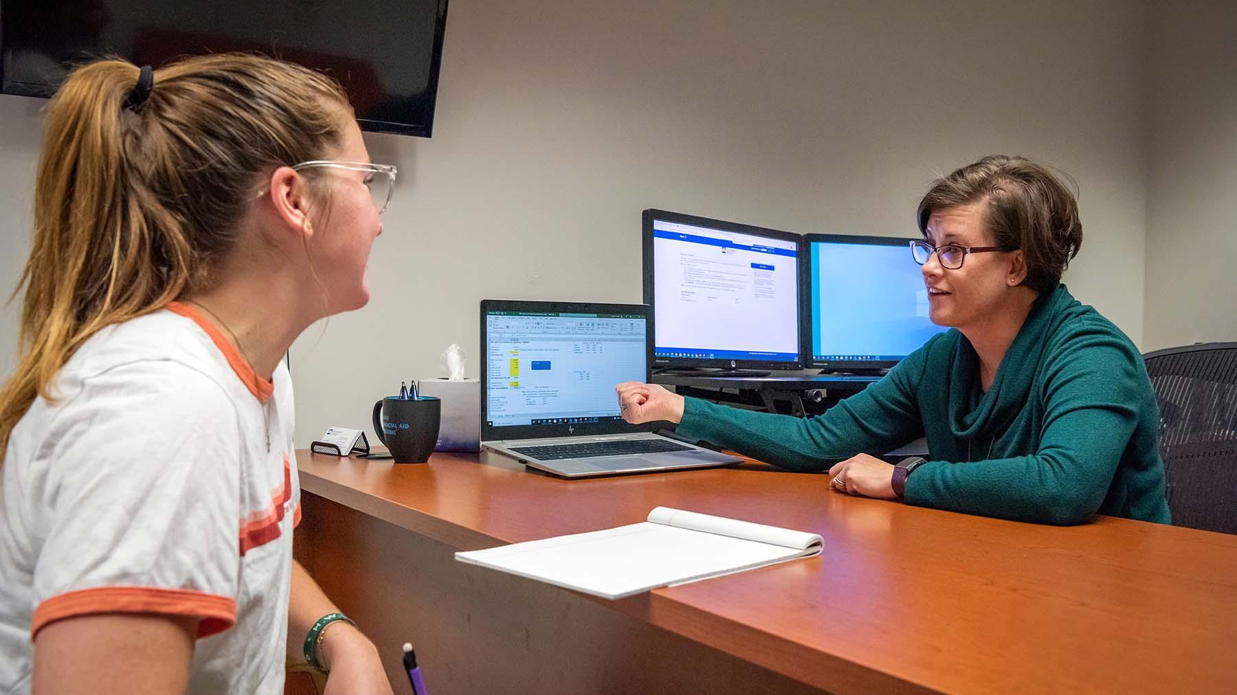 Financial aid representative meeting with student in her office.