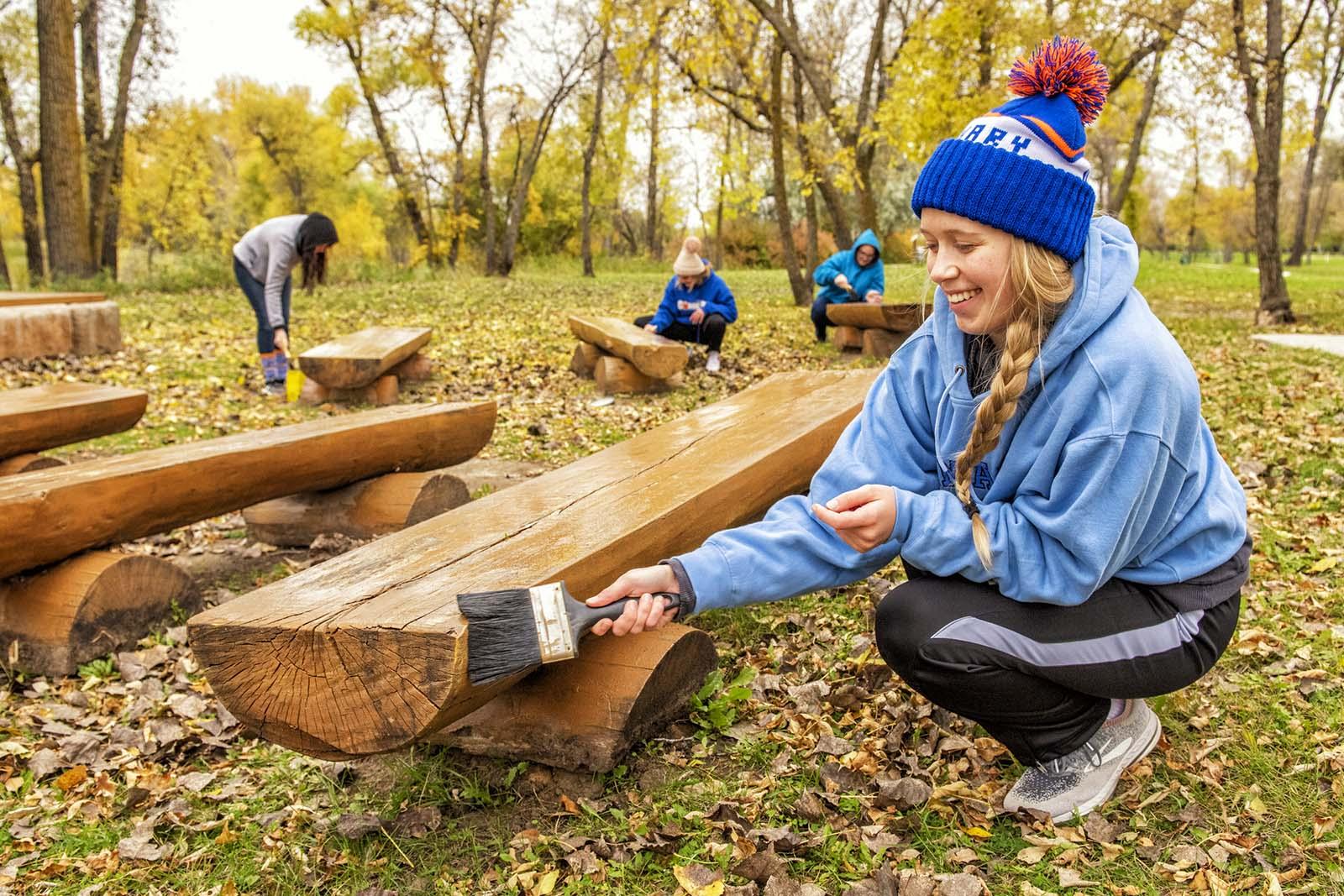 Student painting a bench during Day of Service