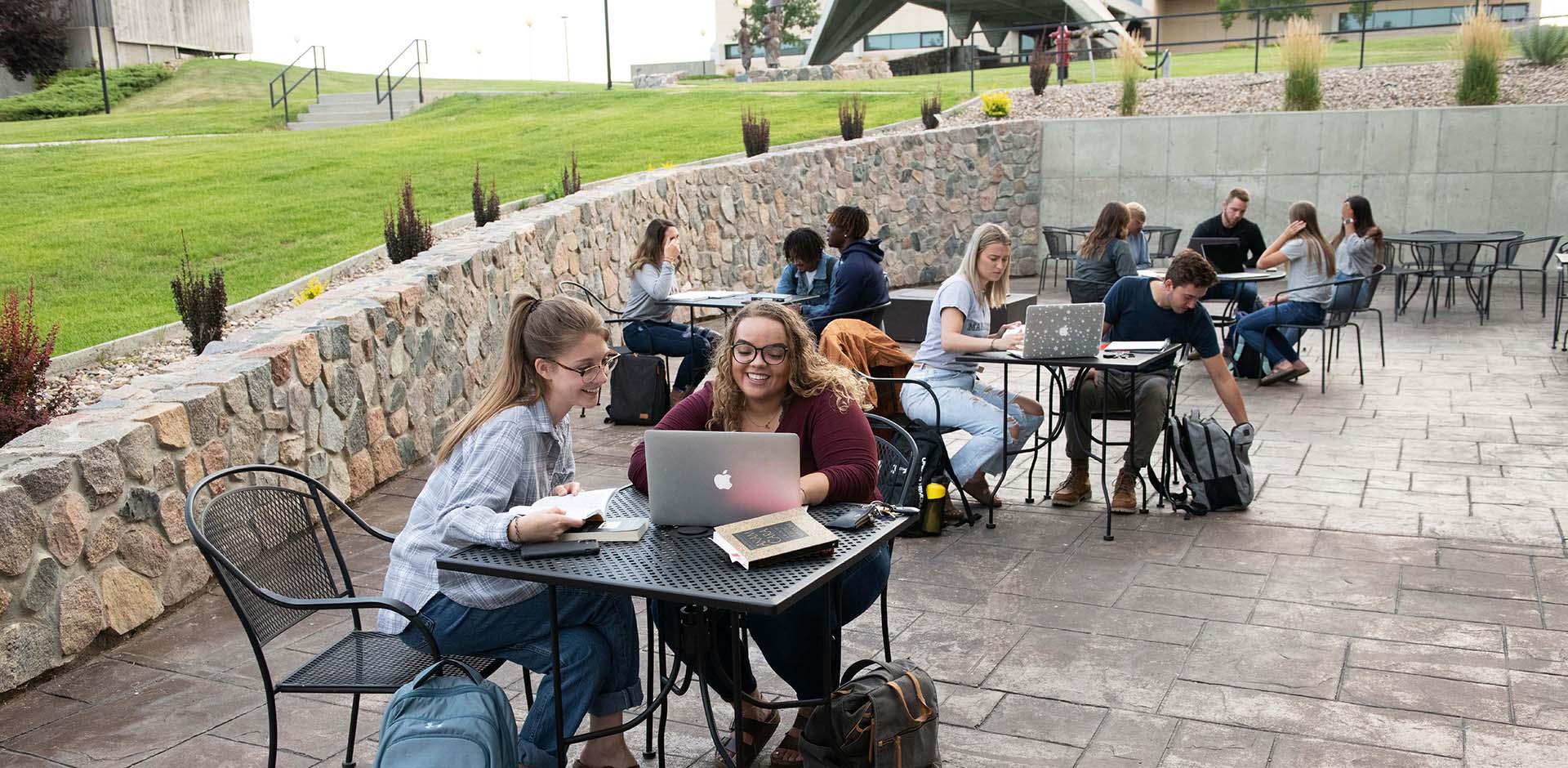 Students studying outside at table on patio