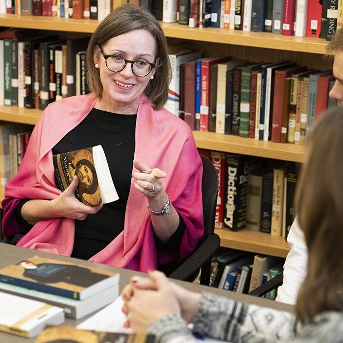 Smiling faculty member leads small class discussion