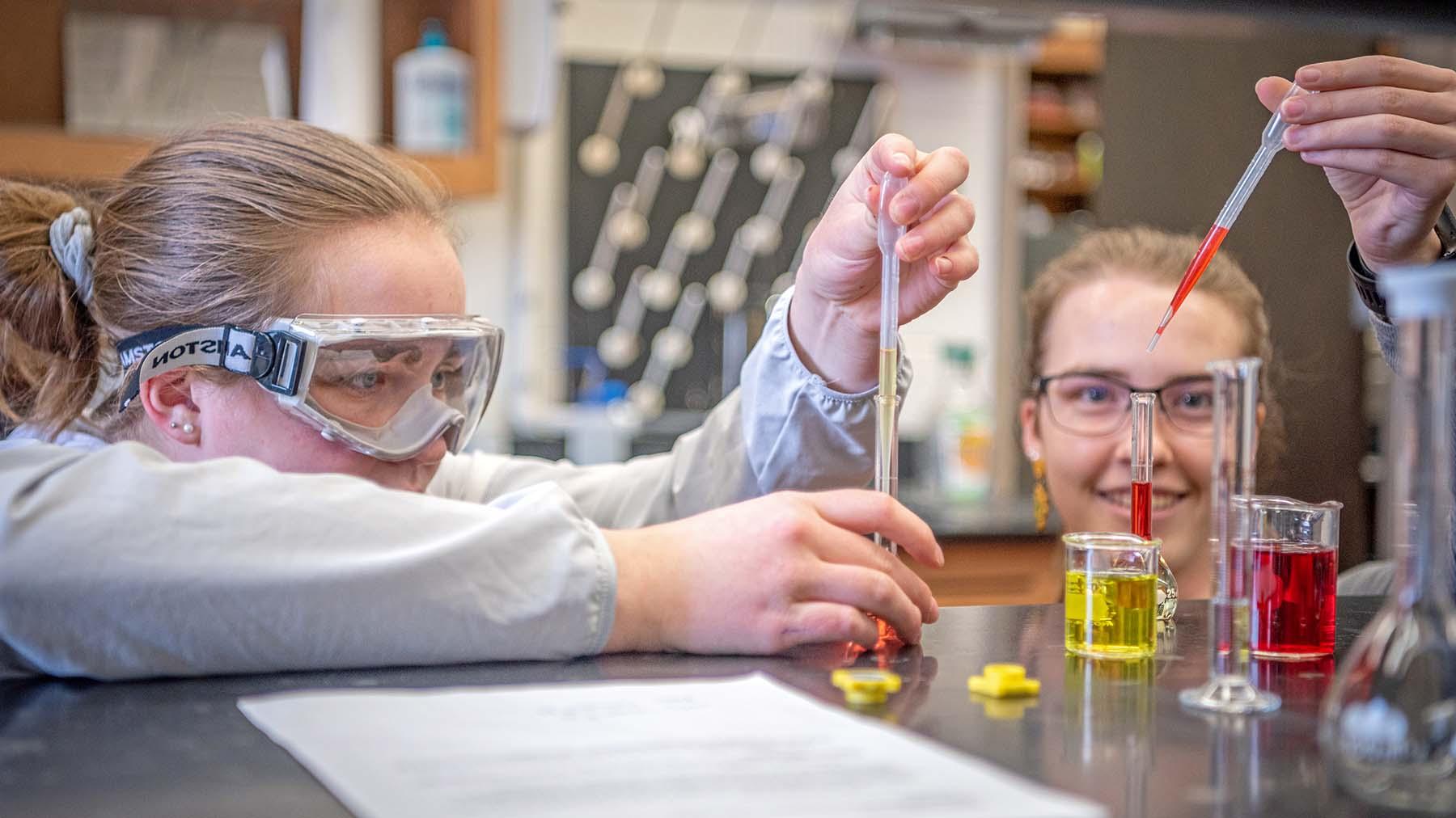 Chemistry students adding liquid to beakers