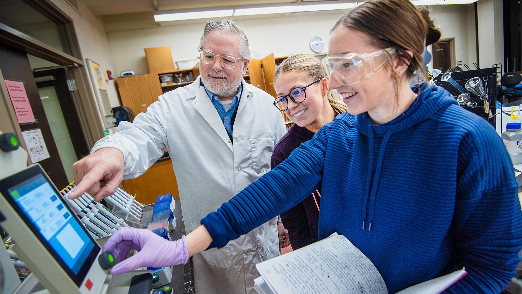 Dr. Peliska working in a lab class with students.