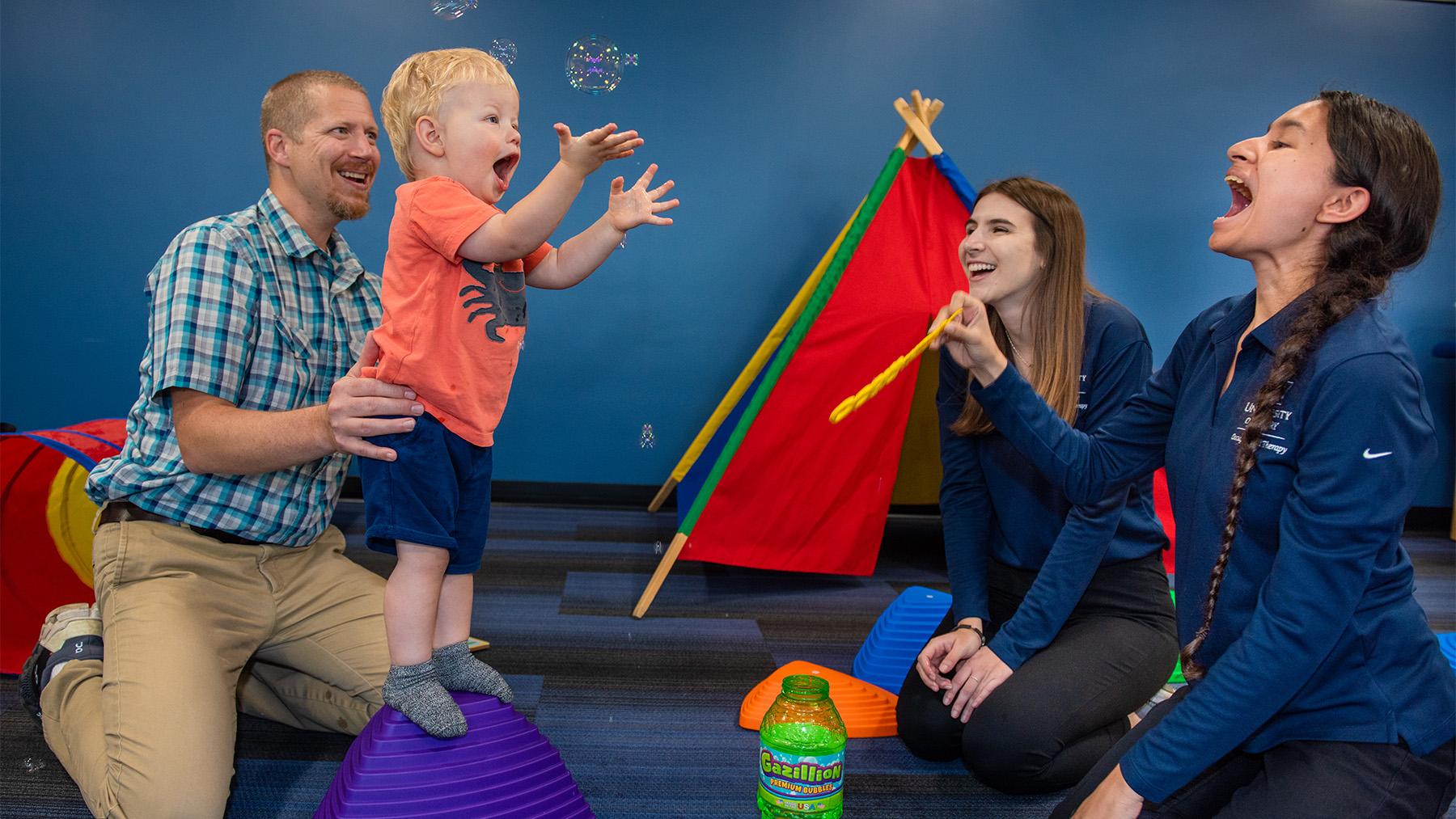 Students working with a young patient in occupational therapy.