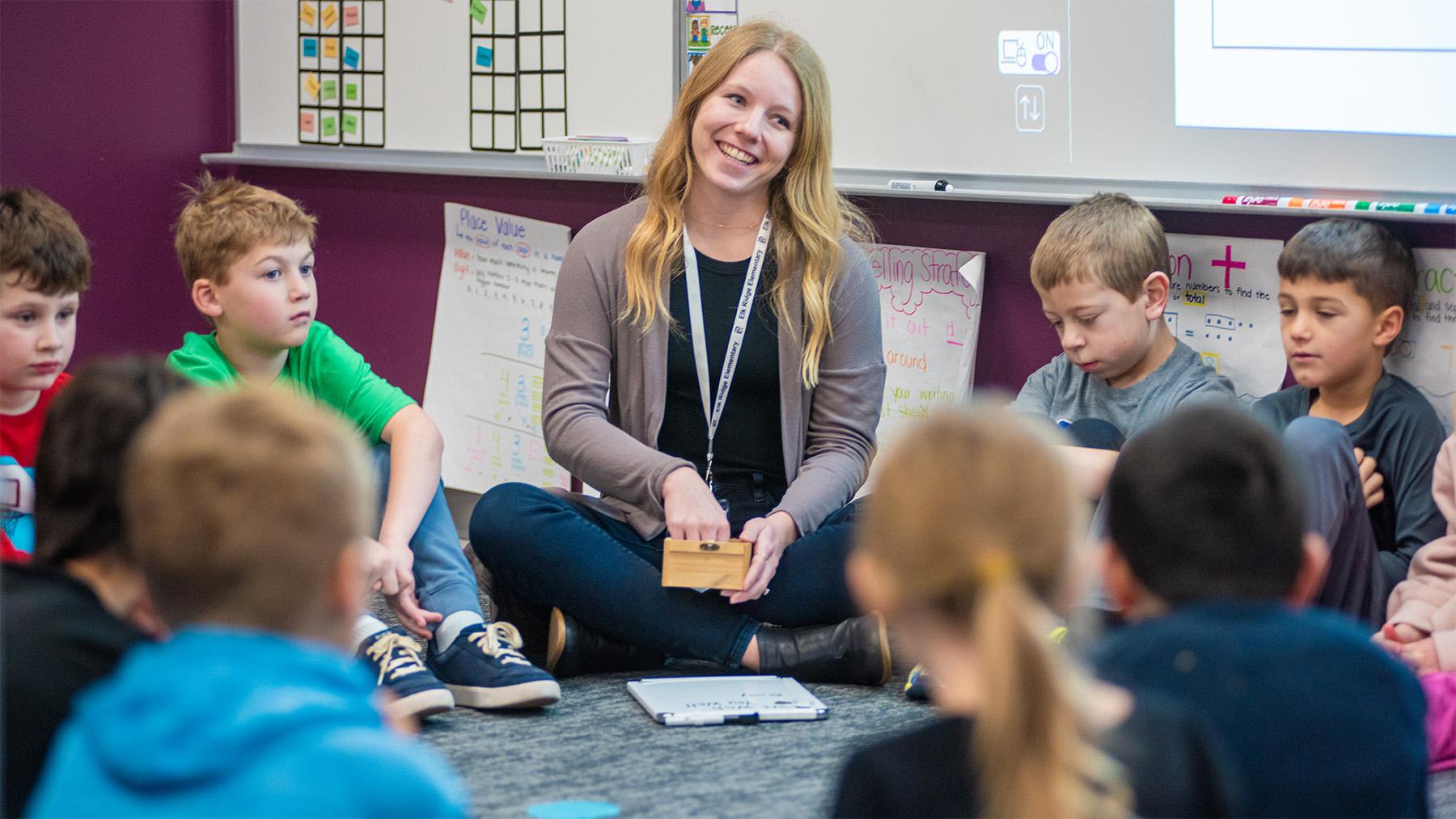 One of our female alumni teaching a lesson on a rug with young students