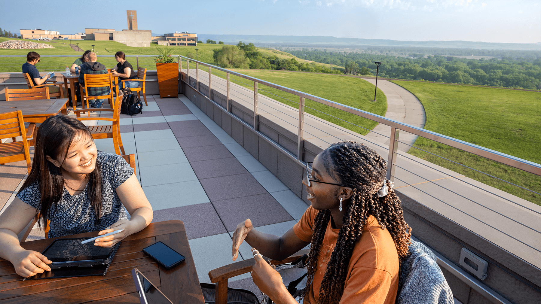 two female students studying on the Lodge patio.