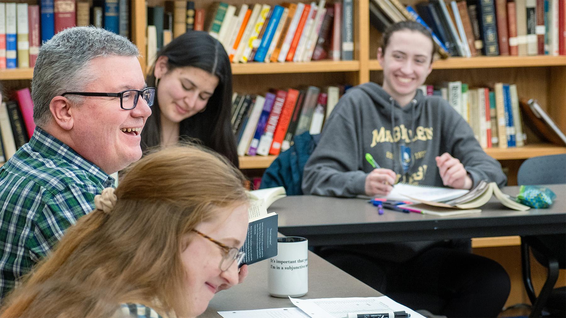 students having class surrounded by books and discussing a book