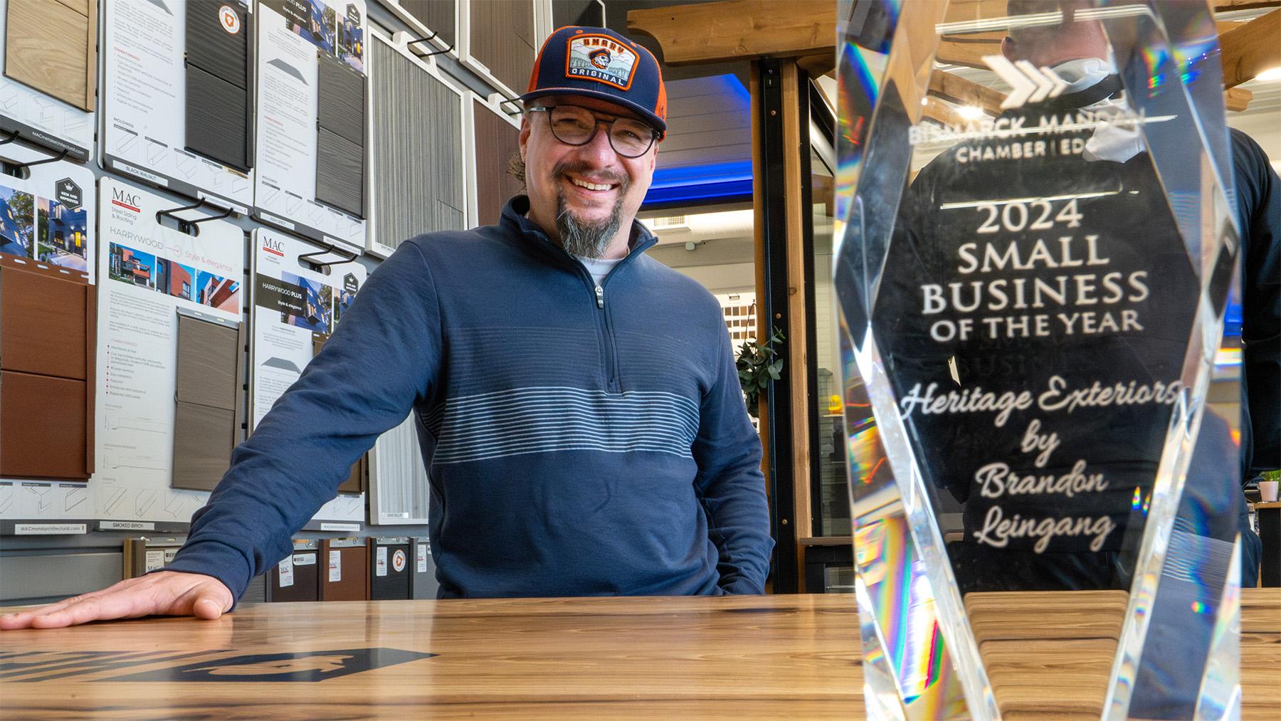 Brandon Leingang standing behind his Small business of the year award