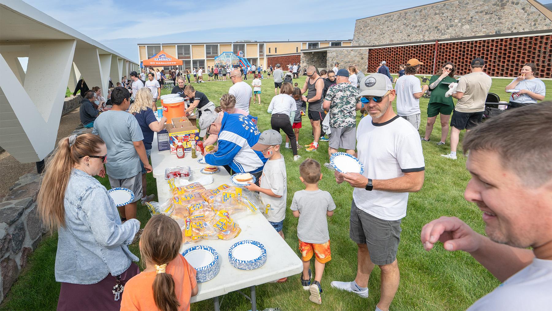 People of all ages getting food at the Alumni picnic