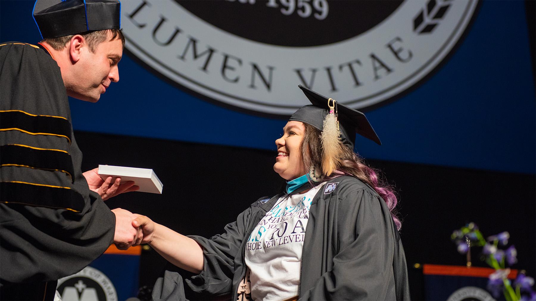 Native American student receiving their diploma at graduation