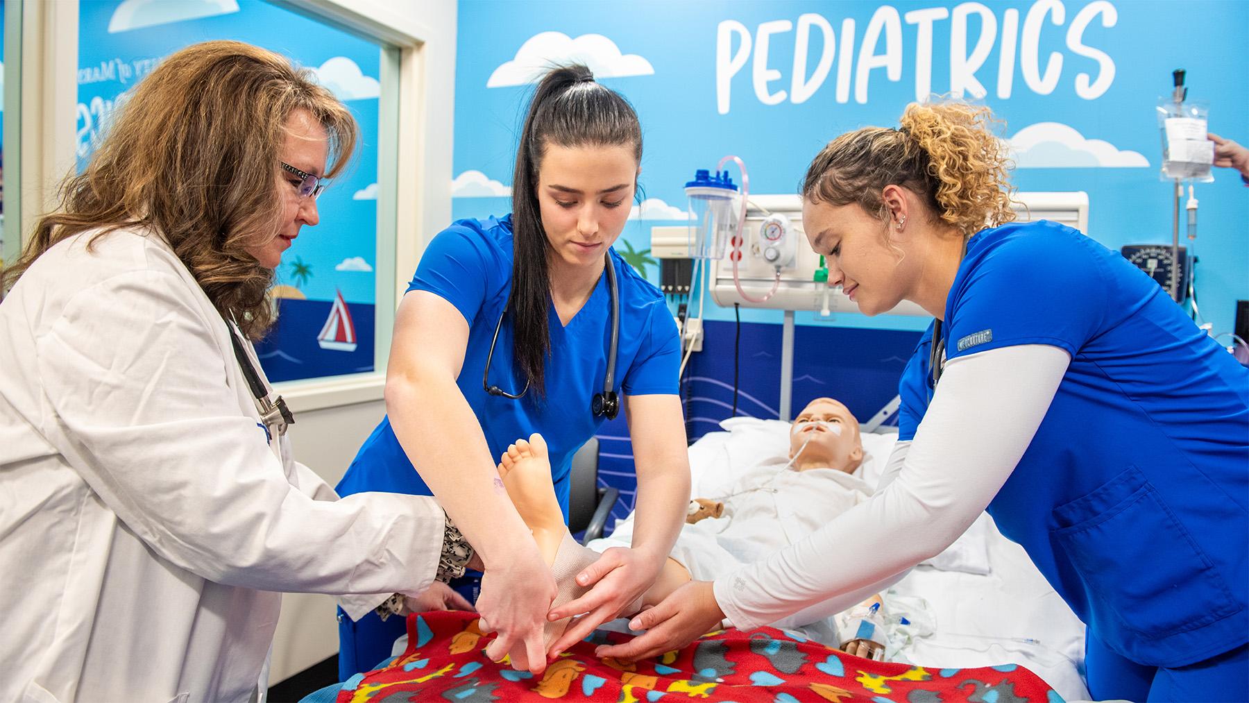 two students working with their instructor in a sim lab